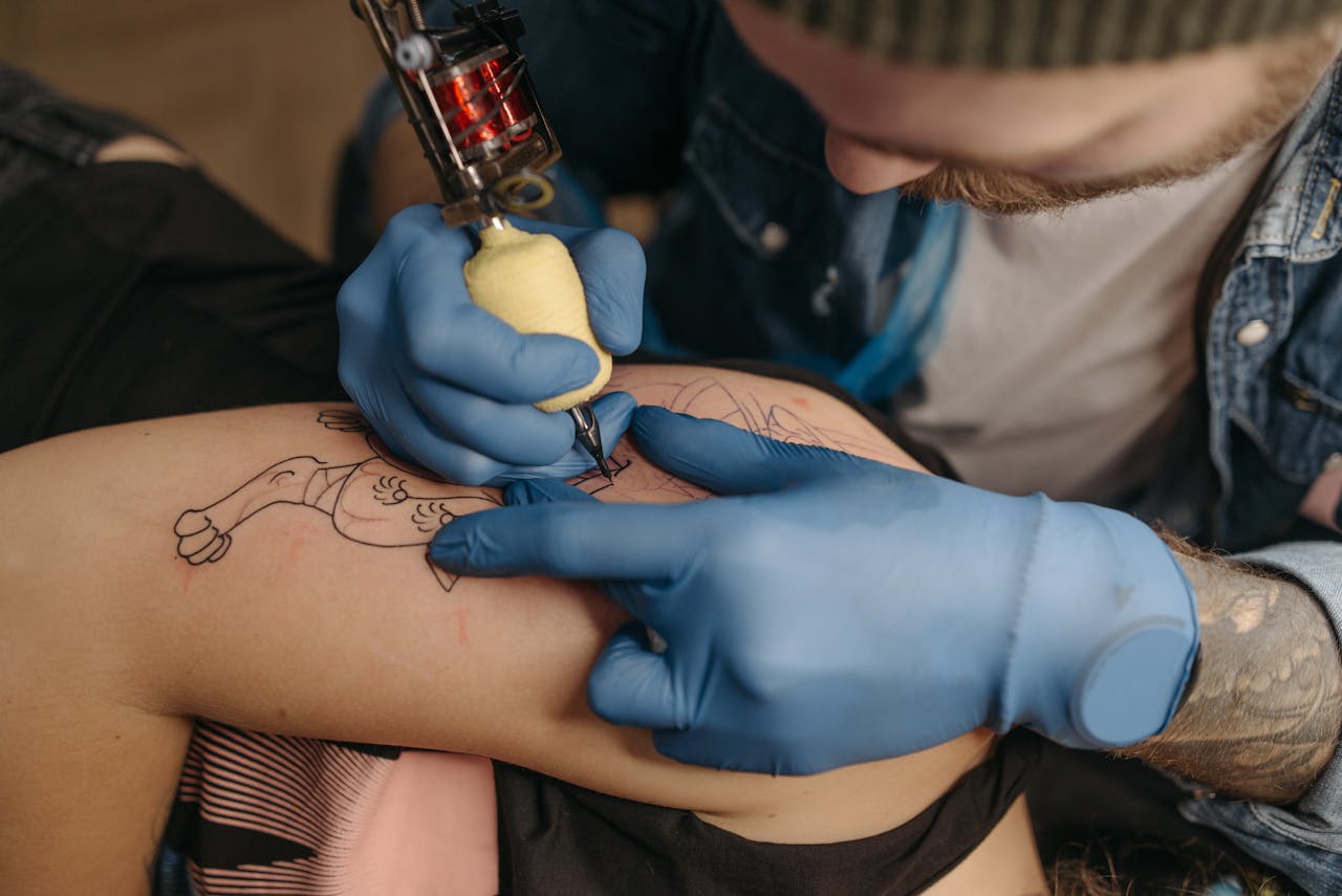 Tattoo artist using a machine to ink a client