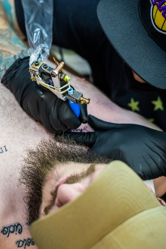 A detailed shot of a tattoo artist working on a man's chest, featuring intricate designs.