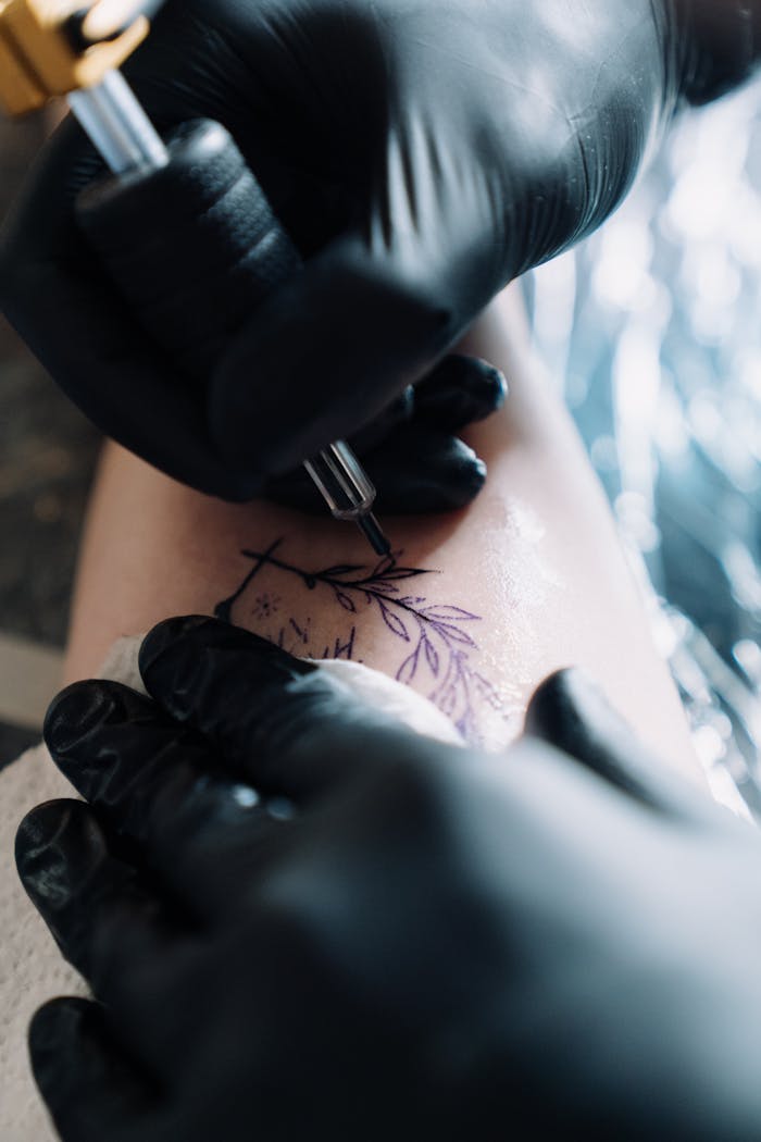 Close-up of a tattoo artist tattooing a floral design on a client's skin.