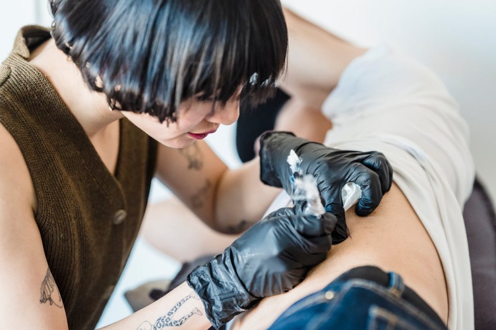 Close-up of a tattoo artist working on a client indoors, focusing on precision and technique.
